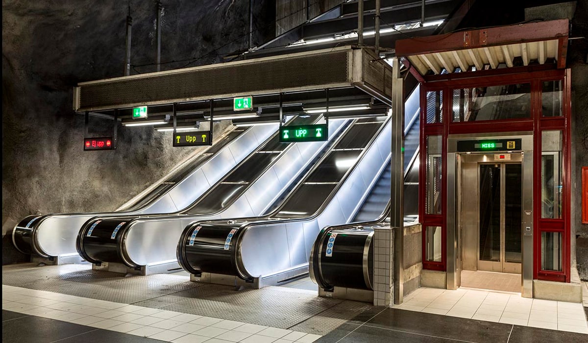 Tre rulltrapport som leder från och till en tunnelbaneplattform, vid sidan av finns en hiss.