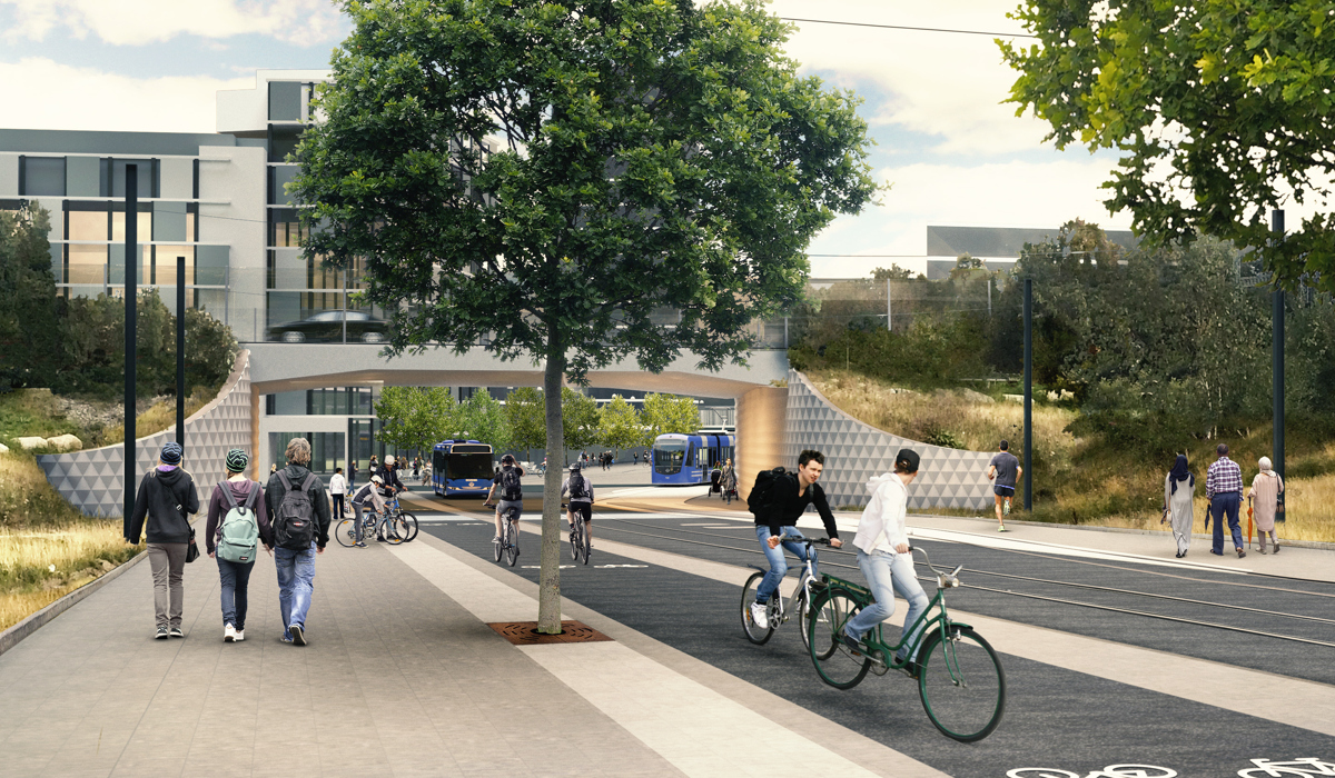 Gång-, cykel och bussväg samt tvärbanespår löper bredvid varandra under en vägport. Flera personer cyklar och går.