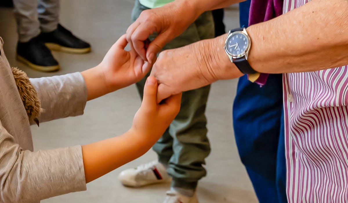 Barn och äldre personer håller varandras händer