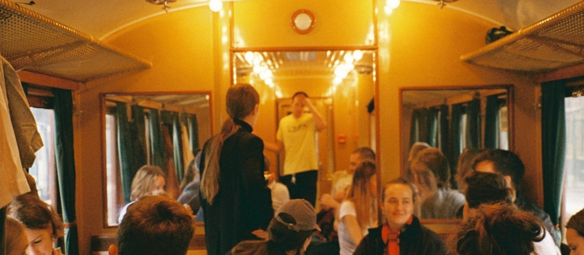 En grupp m&auml;nniskor som sitter i en gammal t&aring;gvagn.