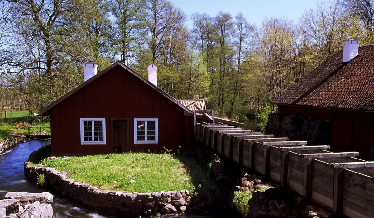 Ett litet r&ouml;tt tr&auml;hus intill en fors.