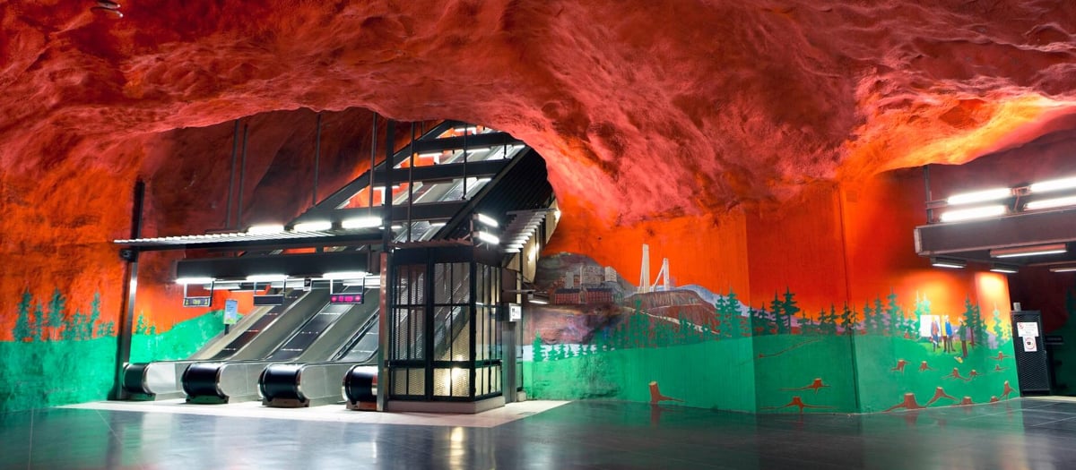 Bergrum med r&ouml;tt tak och gr&ouml;n m&aring;lad gr&ouml;nska n&auml;rmast golvet p&aring; Solnas Centrums tunnelbanestation.