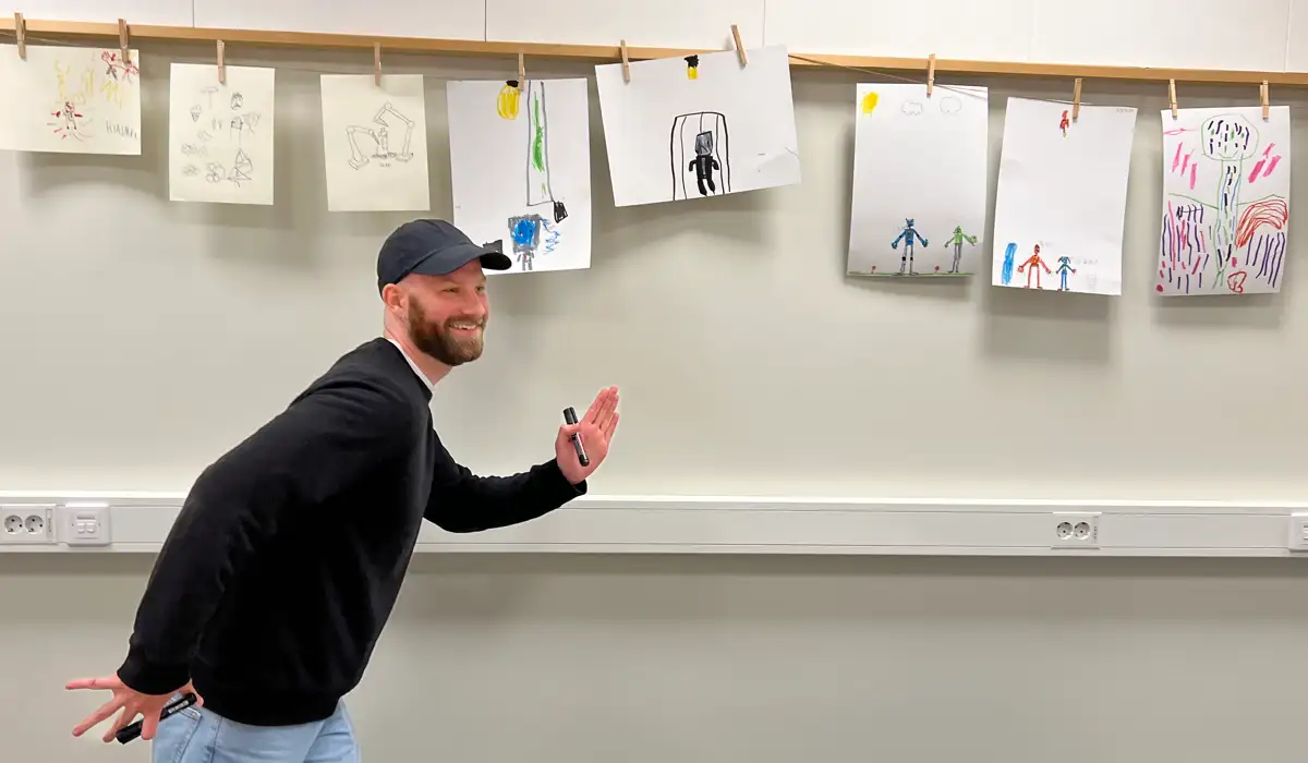 Vidar framför vägg med barnteckningar.