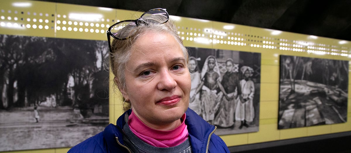 Kvinna framf&ouml;r svartvita m&aring;lningar med fotokarakt&auml;r.