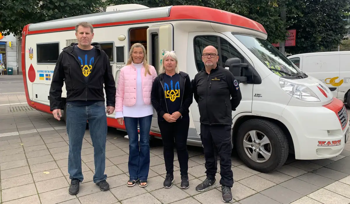 Foto på blodbussen som ska skänkas till Ukraina. Framför bussen står fler personer och tittar in i kameran.
