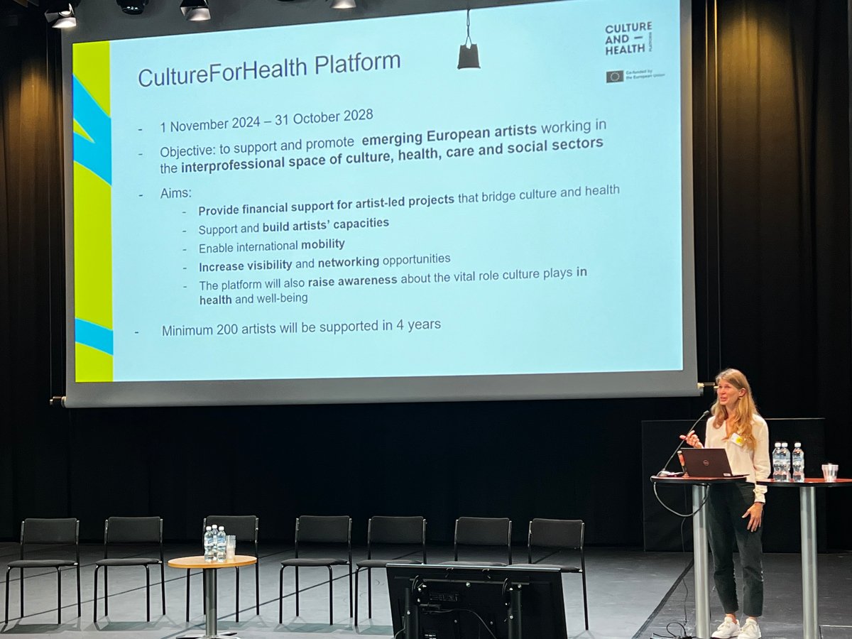 En kvinna står på ett podium framför en folkmassa.