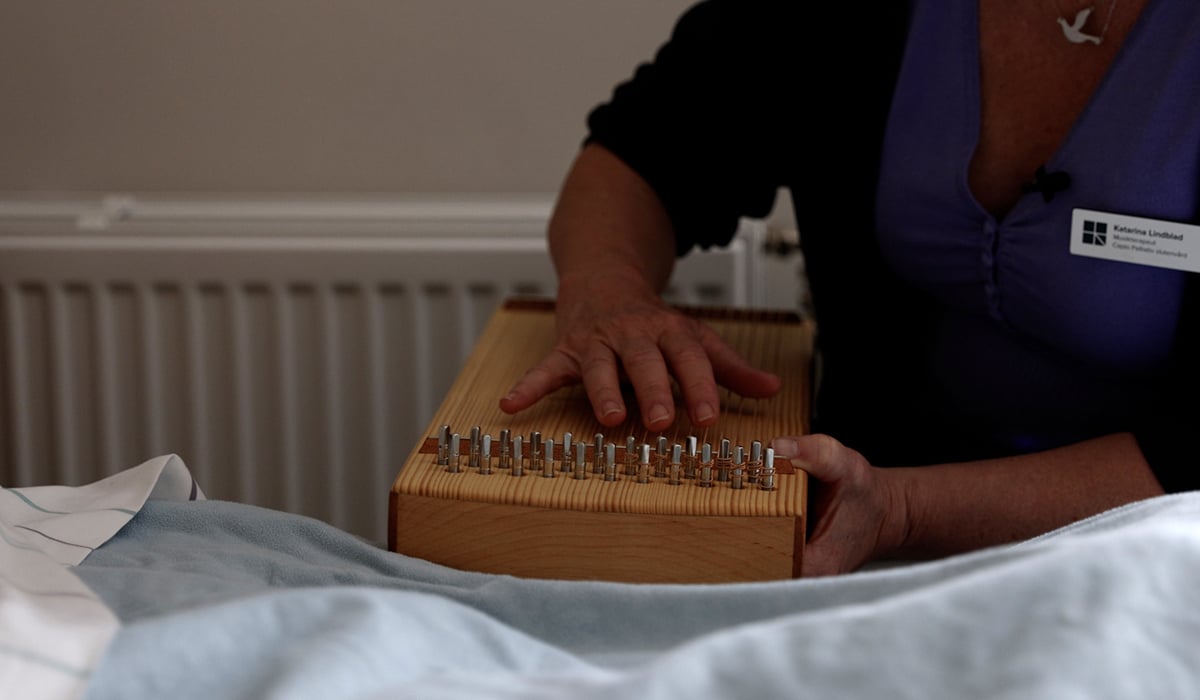 En kvinna spelar ett musikinstrument på en säng.