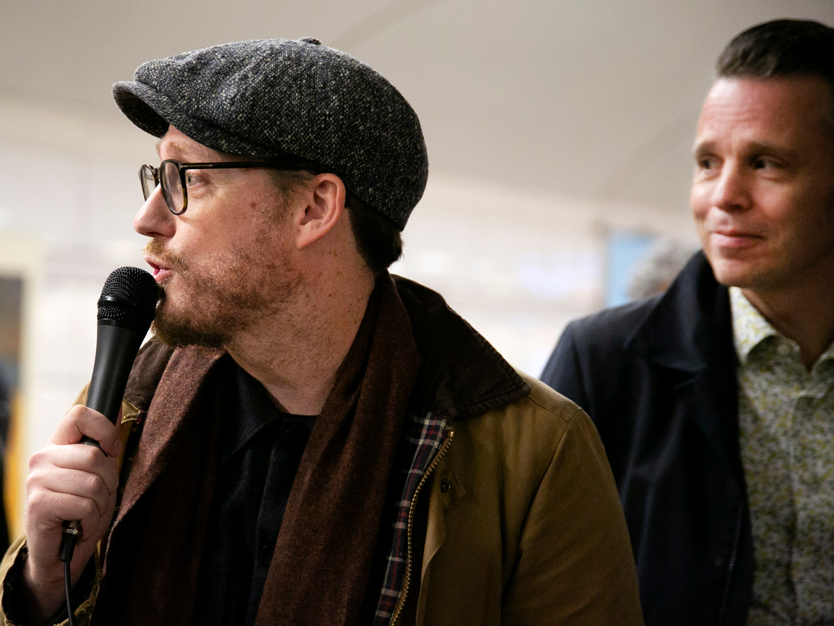 En man håller i en mikrofon medan han står bredvid en annan man.