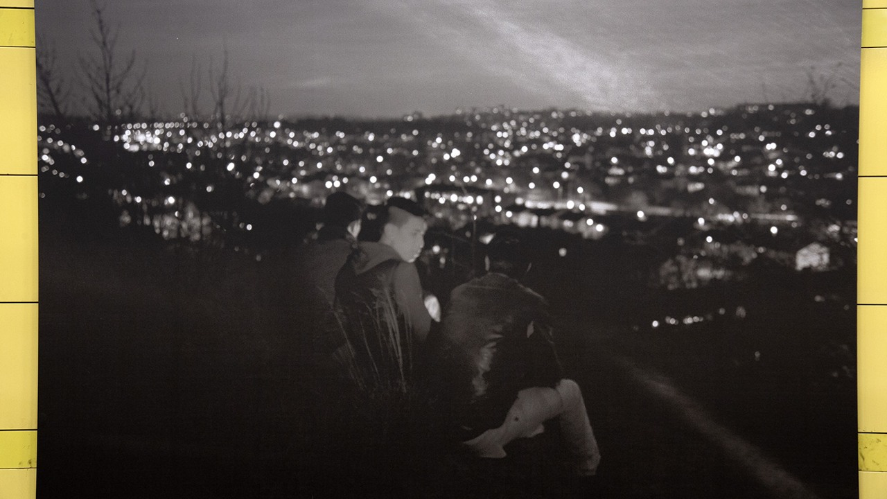 svart-vitt foto av pojkar som tittar ut över stadens ljus på kvällen