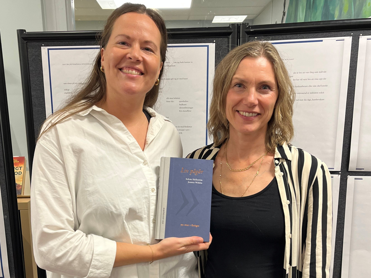 Biblioteksmedarbetarna Selene och Joannna poserar med boken.