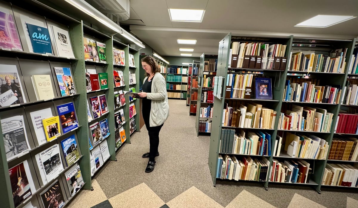 En kvinna som tittar på böcker i ett bibliotek.