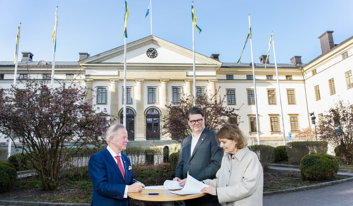 Foto på personer som står vid ett bord och skriver på ett avtal. 