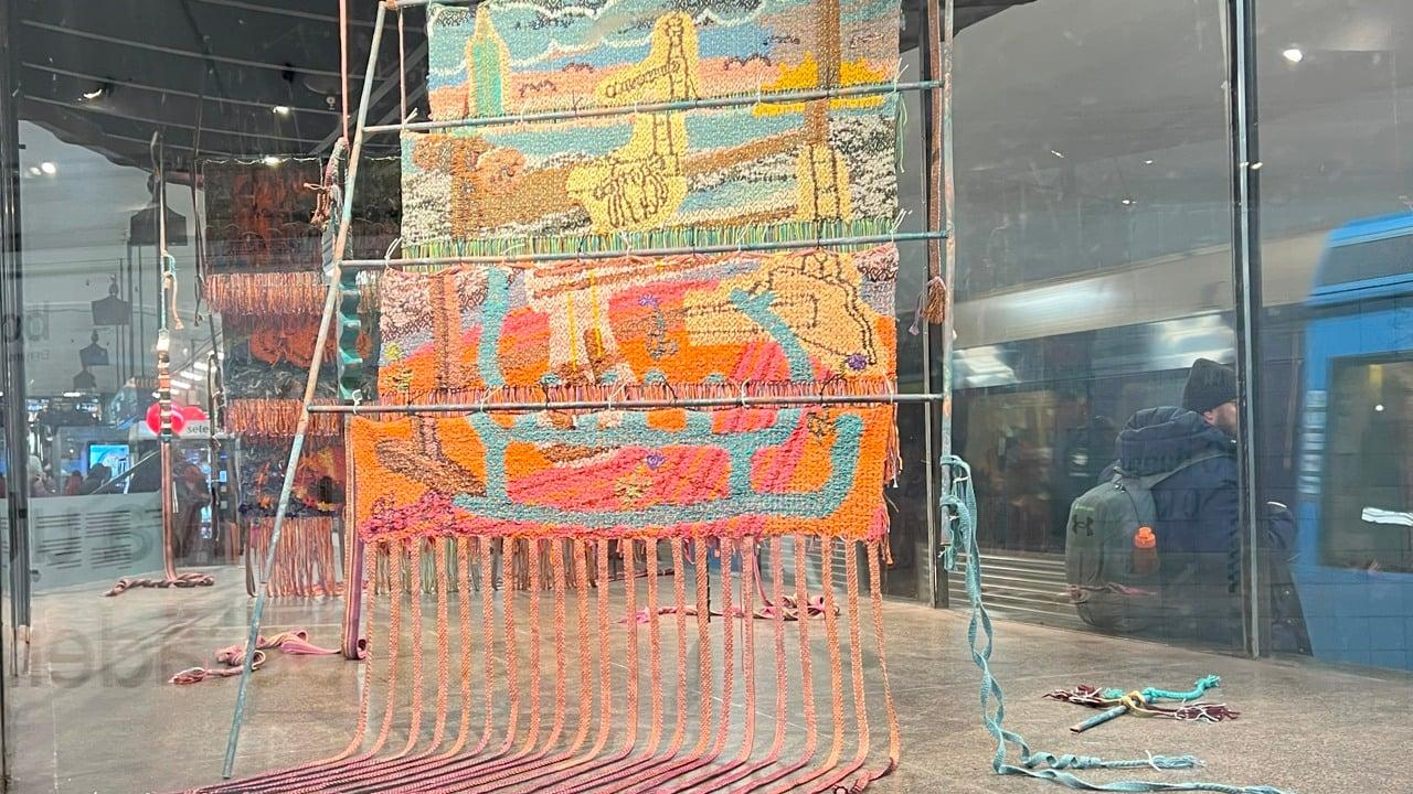 Textil konst på ställning i glasmonter.