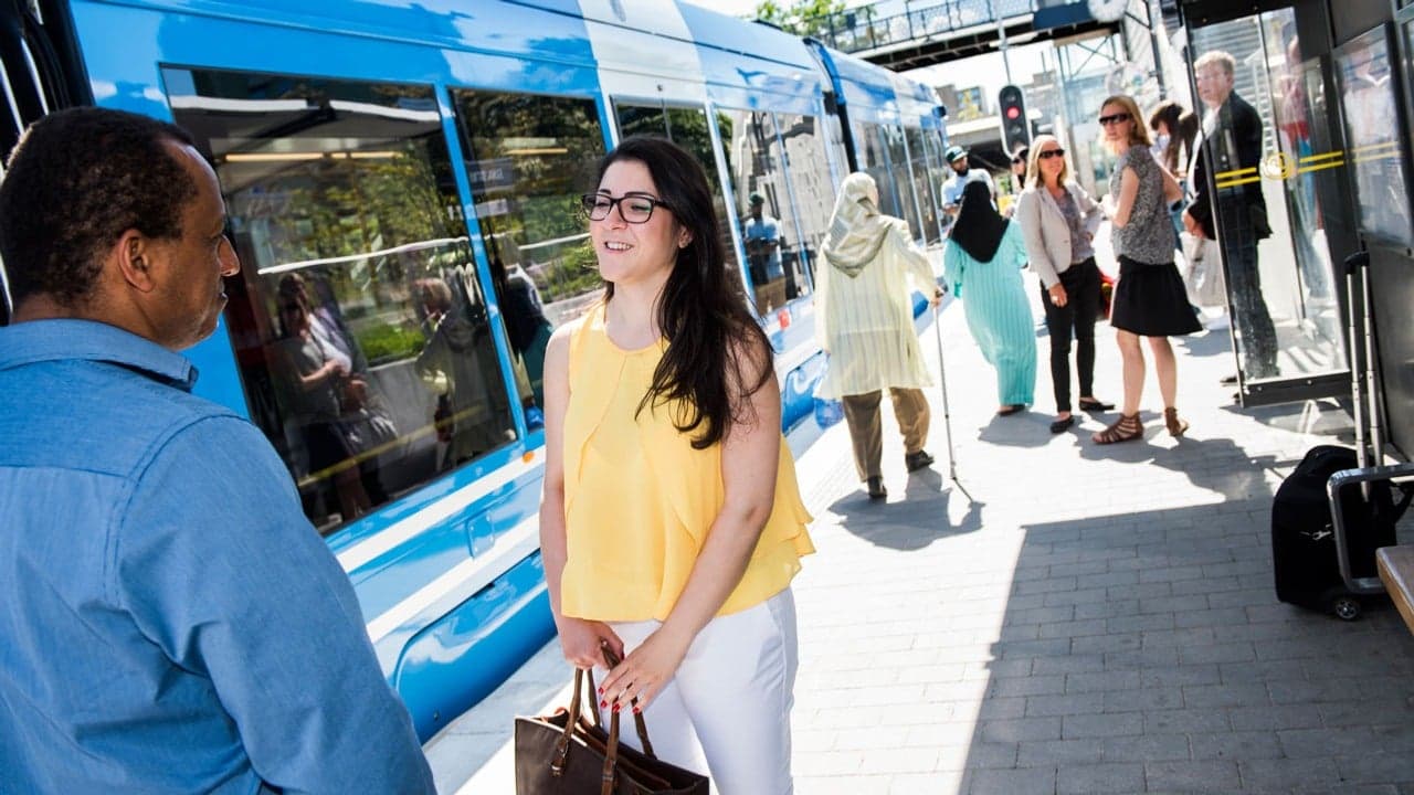 Resenärer på plattform, en spårvagn står på spåret