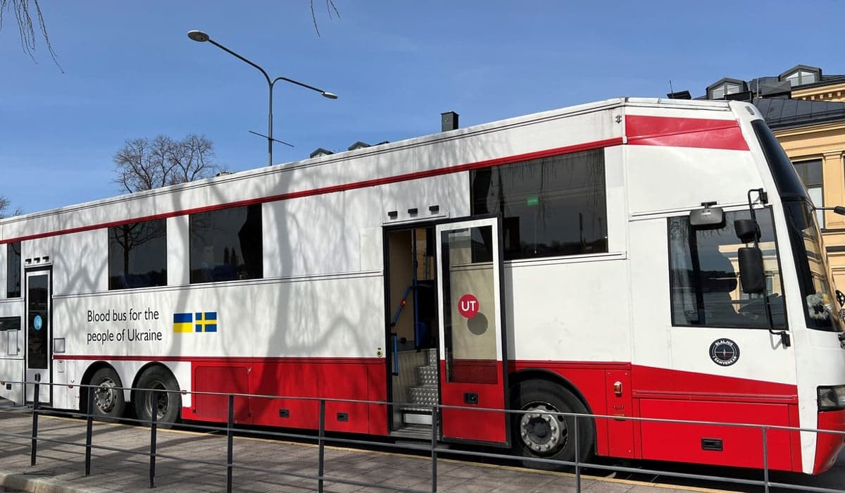 En stor vitröd buss som används som blodbuss. Den står parkerad med öppna dörrar.