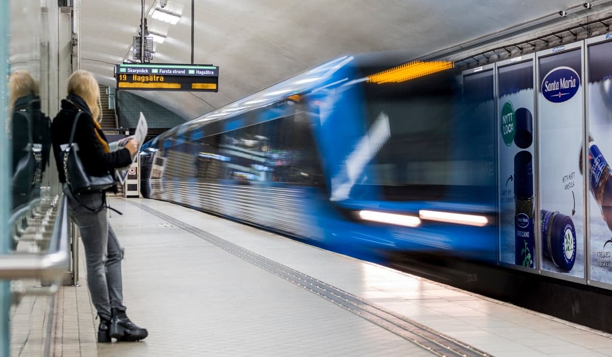 Personer väntar på tunnelbanan som rullar in i hög fart