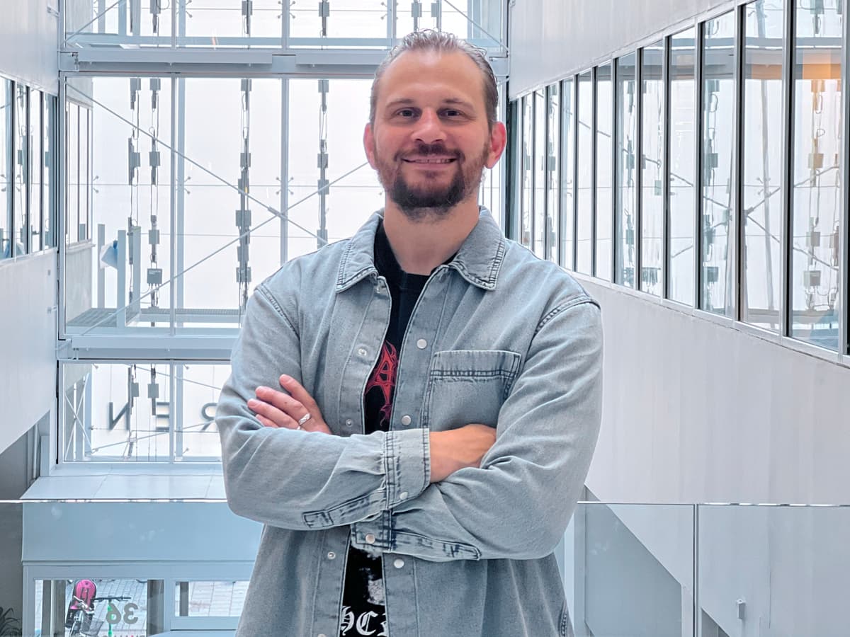 Olof står med armarna i kors och tittar in i kameran.