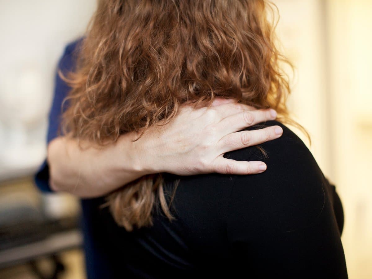 En person håller sin hand på en annan persons axel.