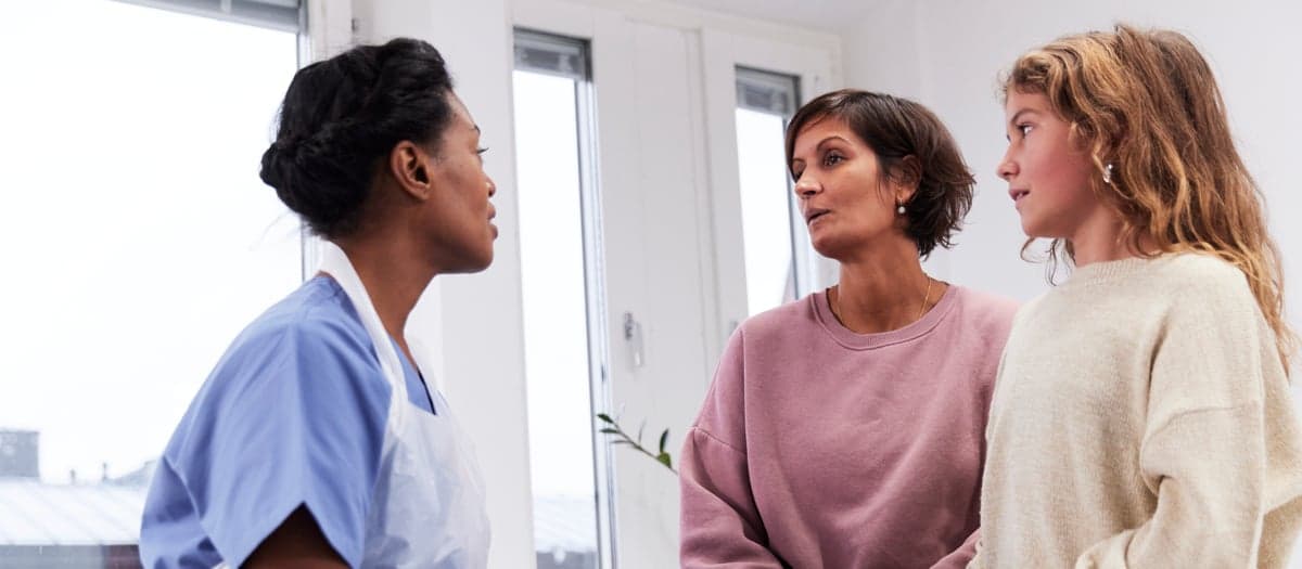 En läkare i samtal med två patienter/ en anhörig och en patient.