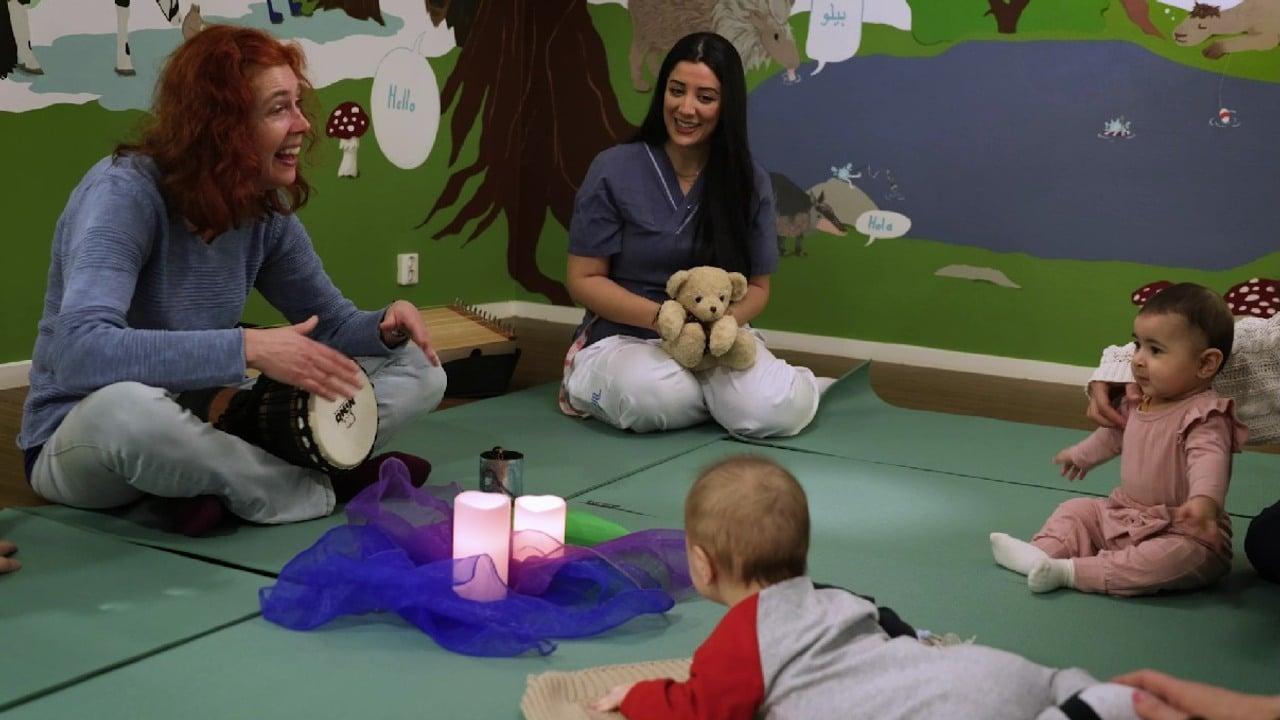 bebisar på golvet framför musikterapeut och sköterska