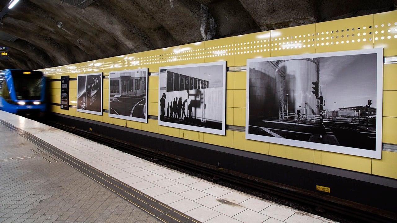 tåg på Fridhemsplan framför svart-vita foton på rad