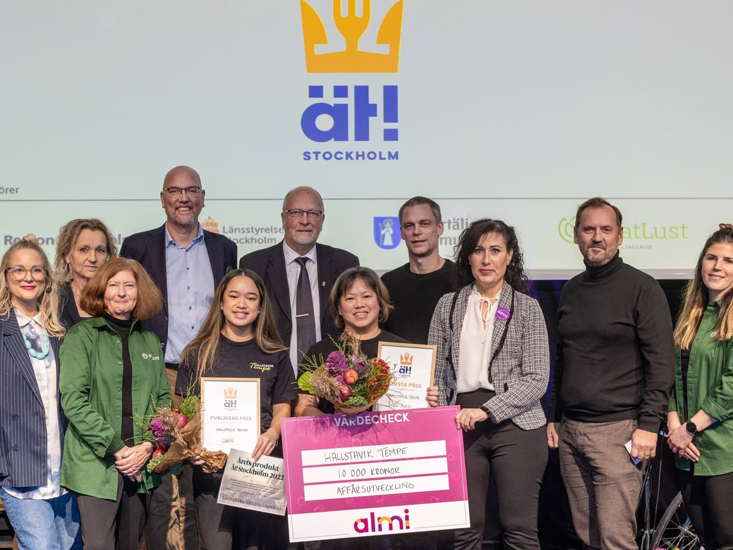 Personer som står uppradade och håller upp en rosa vinnarcheck. 