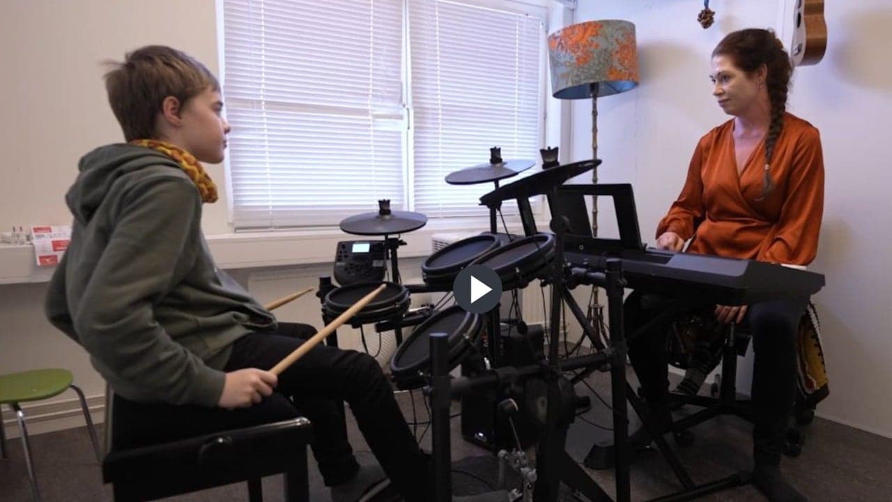 pojke spelar trummor och kvinna spelar elpiano