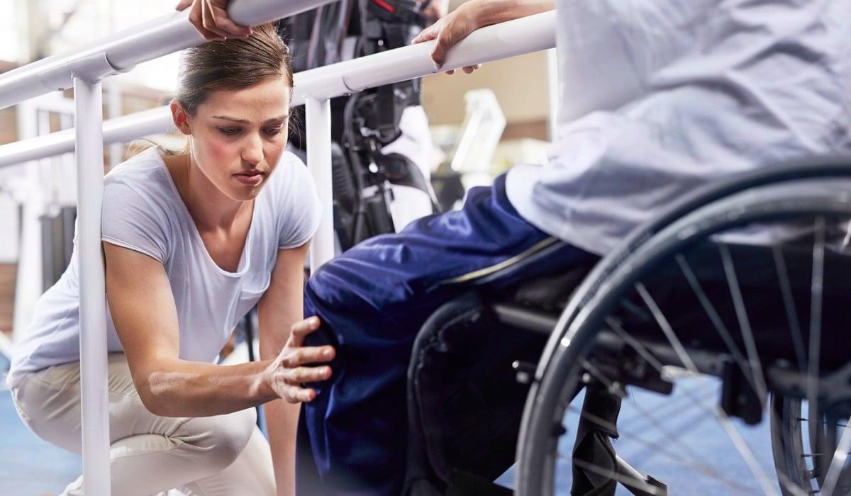 En medarbetare undersöker en patient som sitter i rullstol