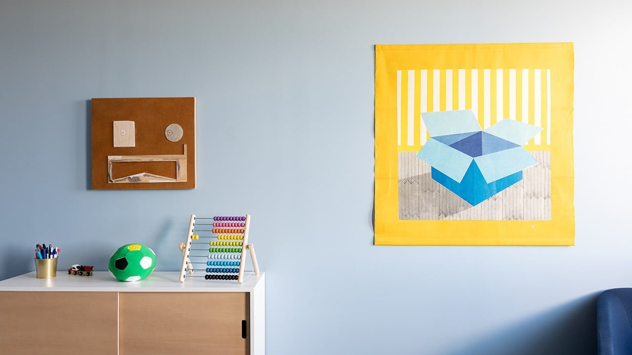 Två tavlor på vägg. I rummet står en byrå med leksaker.