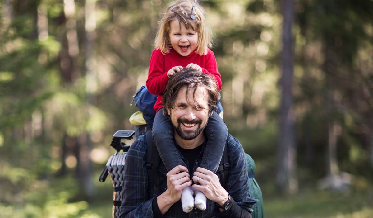 En man som bär en liten flicka på sina axlar.