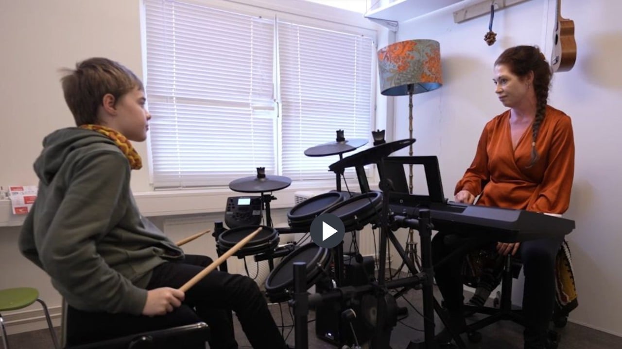 Pojke spelar trummor mittemot kvinna vid keyboard.