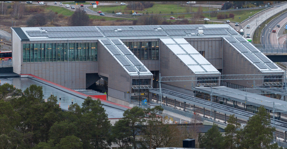 En flygbild av en pendeltågstation med en bro i bakgrunden.