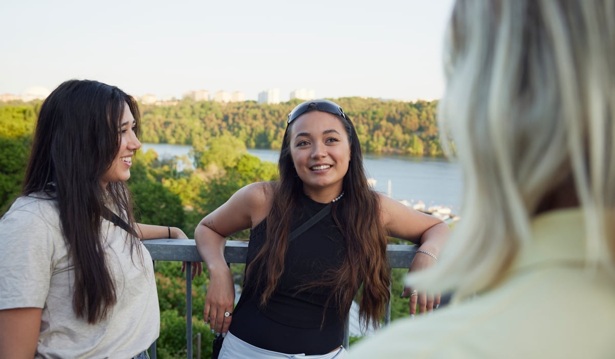 Foto på tre unga kvinnor som står och pratar