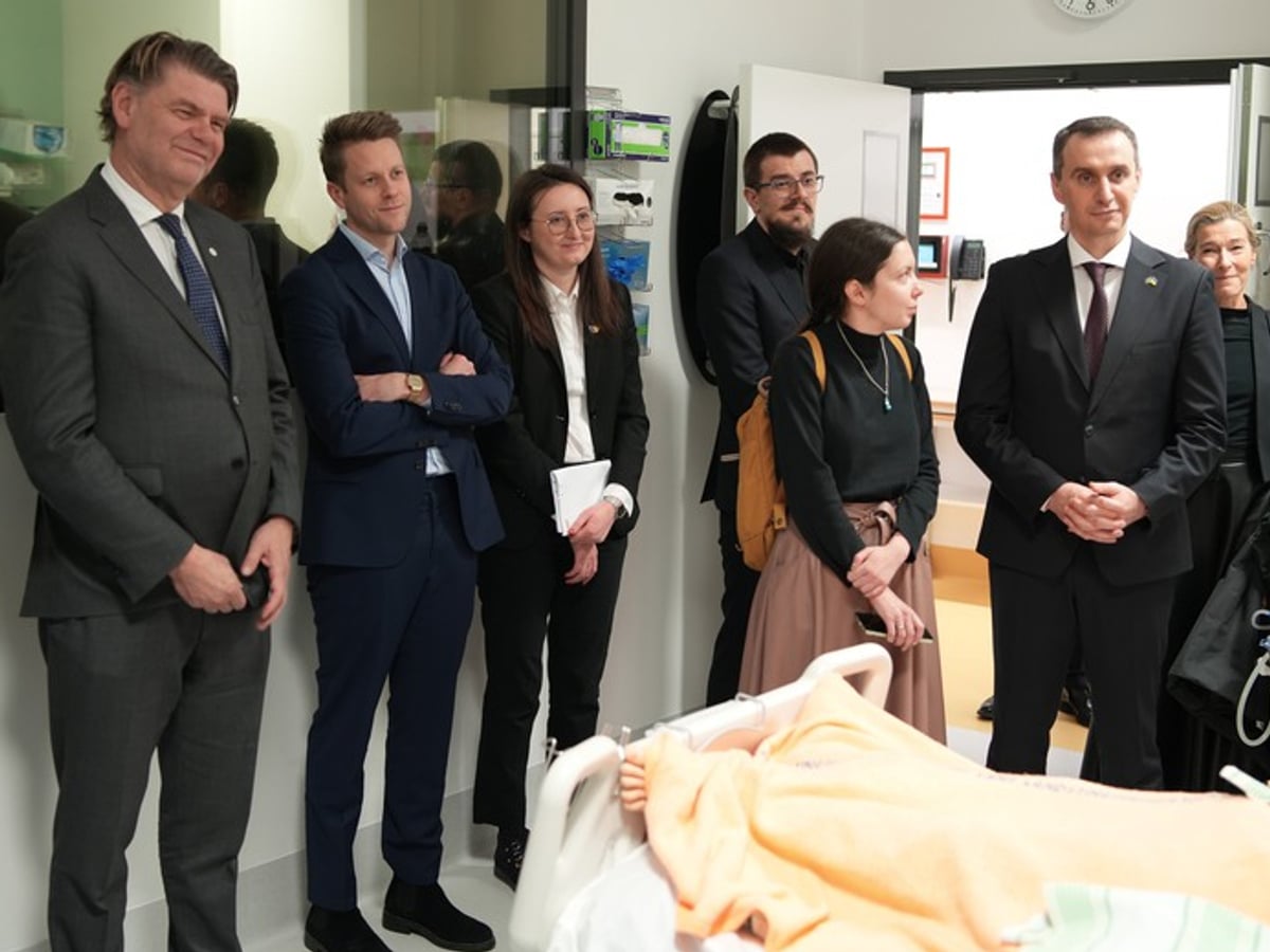 Personer som besöker Karolinska universitetssjukhuset. De samtalar med varandra i ett vårdrum.