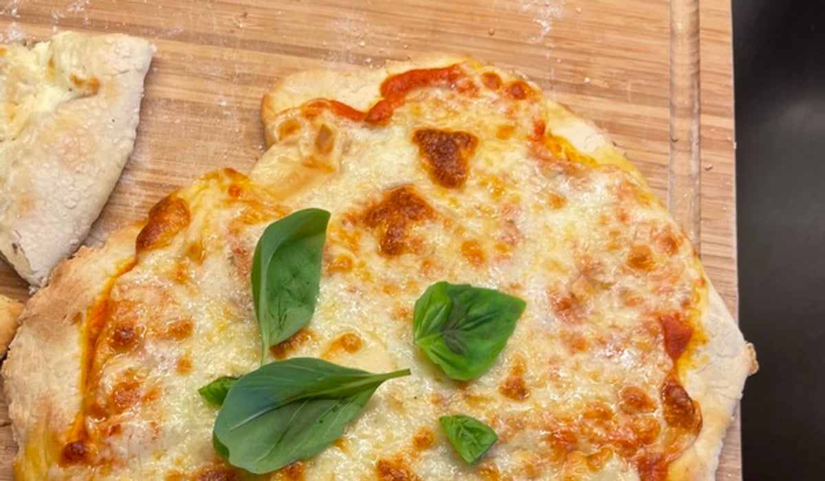 En hemgjord pizza på en skärbräda av trä.