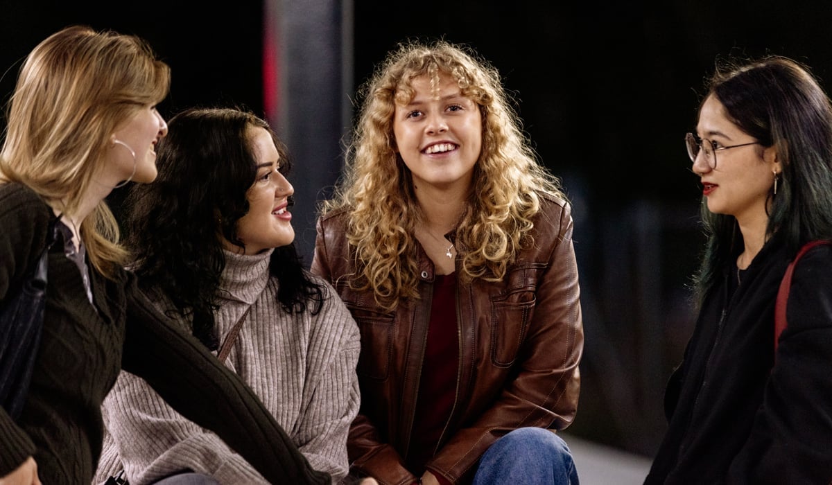 Fyra tjejer är på en perrong i kollektivtrafiken.