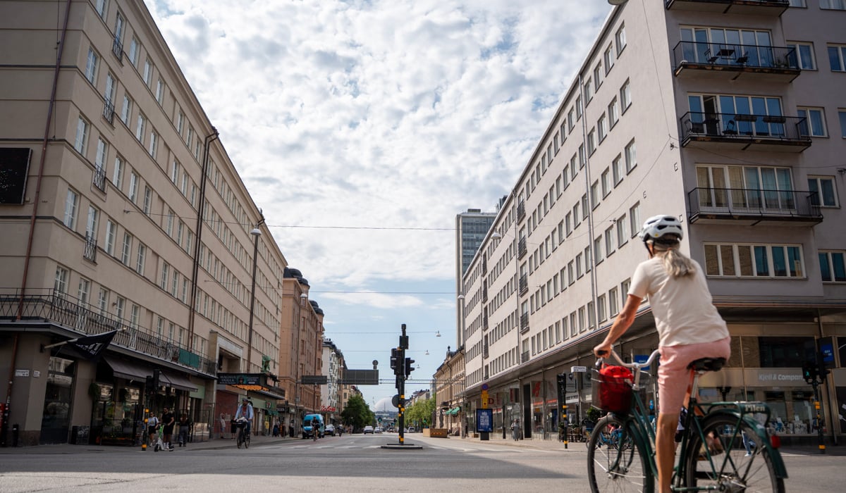 Gatuvy av Götgatan. En kvinna cyklar längs de höga byggnaderna utmed med gatan.