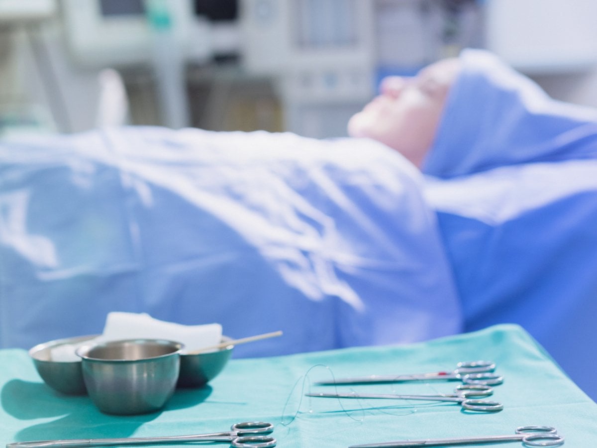 Patient på operationsbord, operationsutrustning i förgrunden.