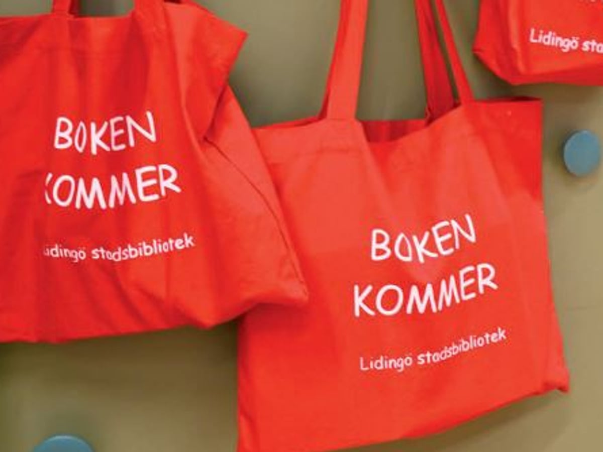 Röda påsar med texten Boken kommer på en vägg. 
