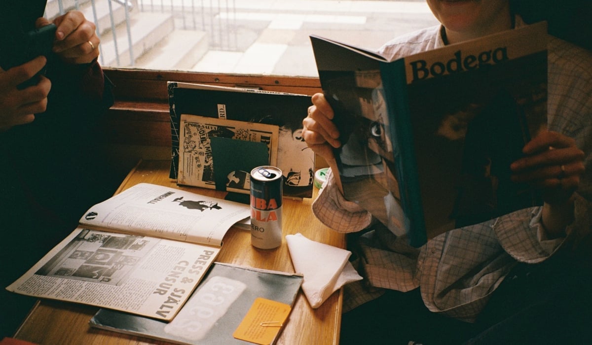 En person som sitter vid ett bord och läser en bok.