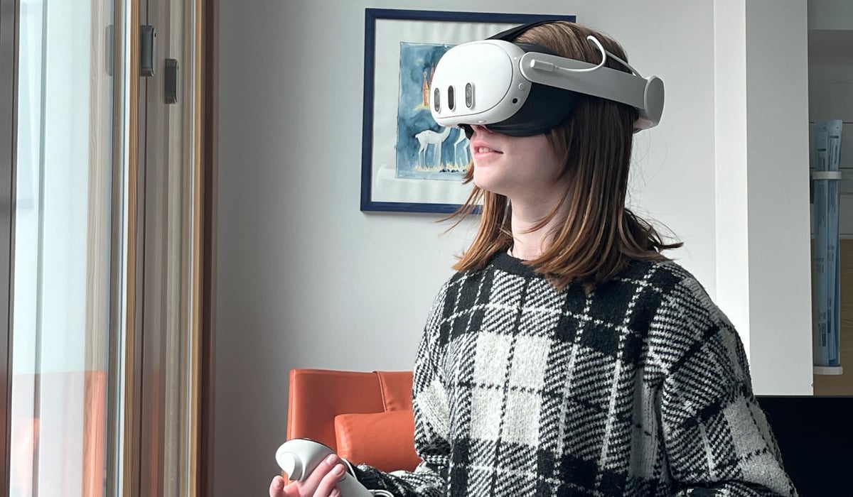 En flicka i 10-årsåldern står med VR-headset och handkontroller i ett sjukhusrum