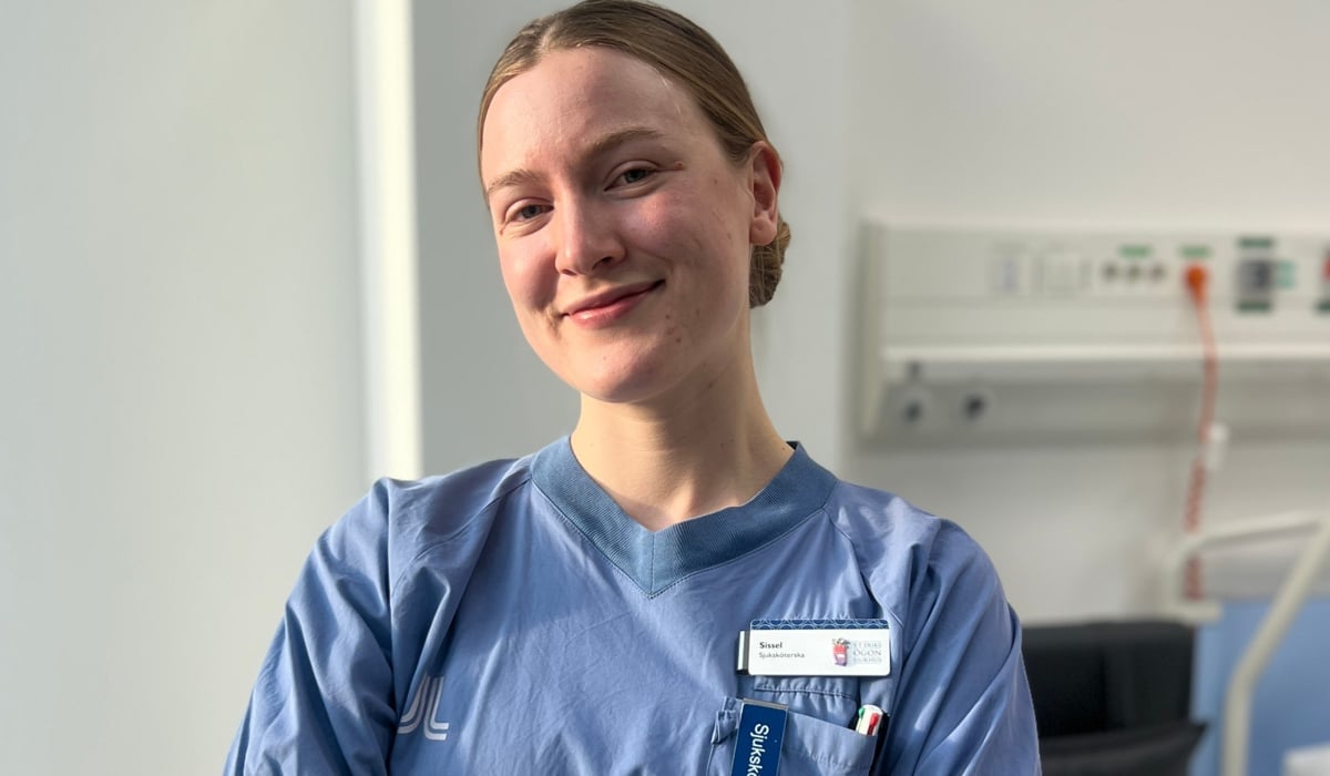 En kvinna i operationskläder står i ett sjukhusrum.