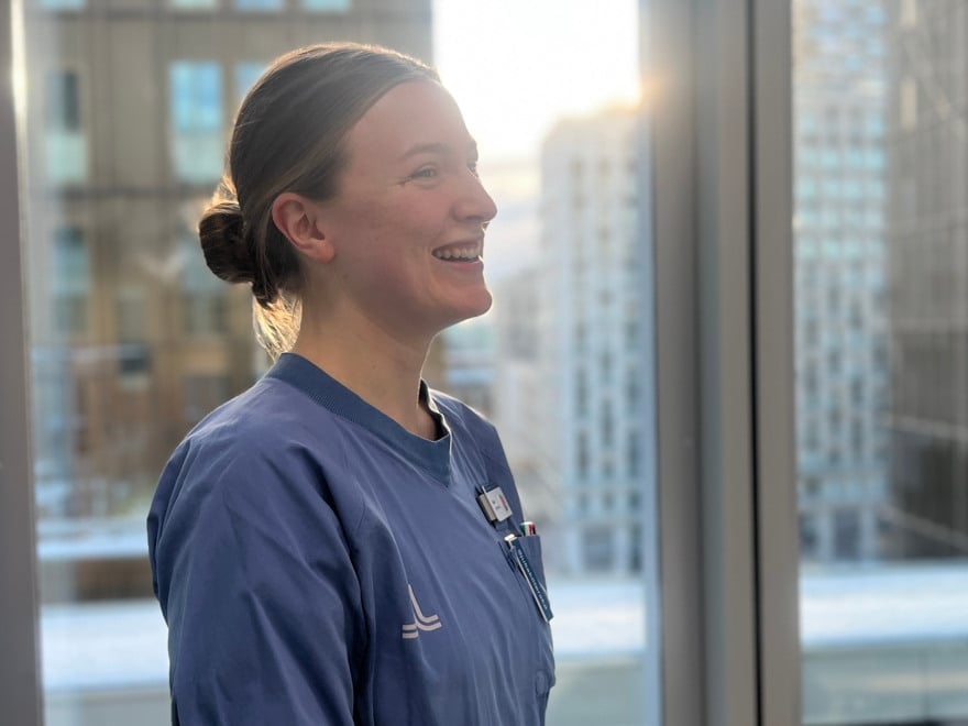 En kvinna i operationskläder står framför ett fönster.