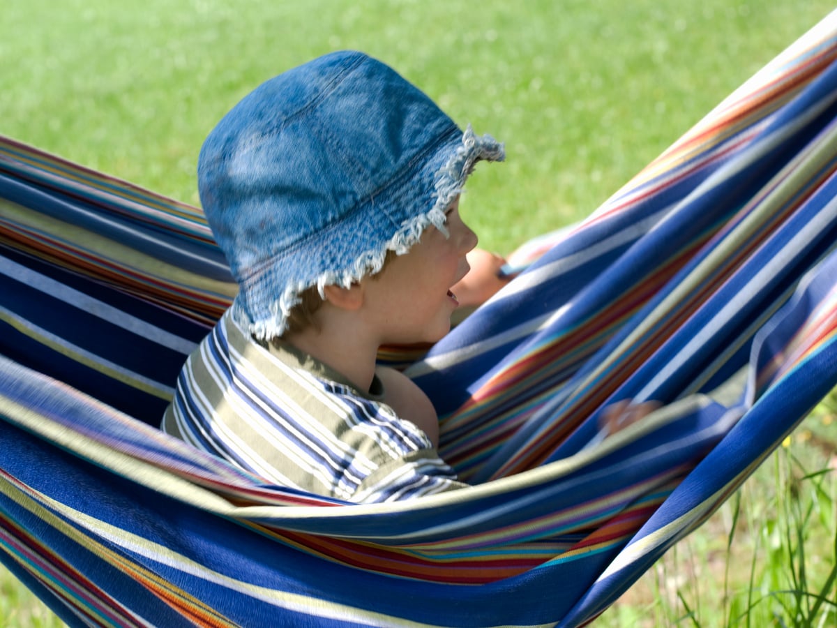 Pojke med solhatt  sitter i en hängmatta.