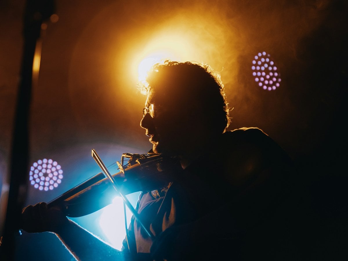 En person i motljus spelar instrument på en scen