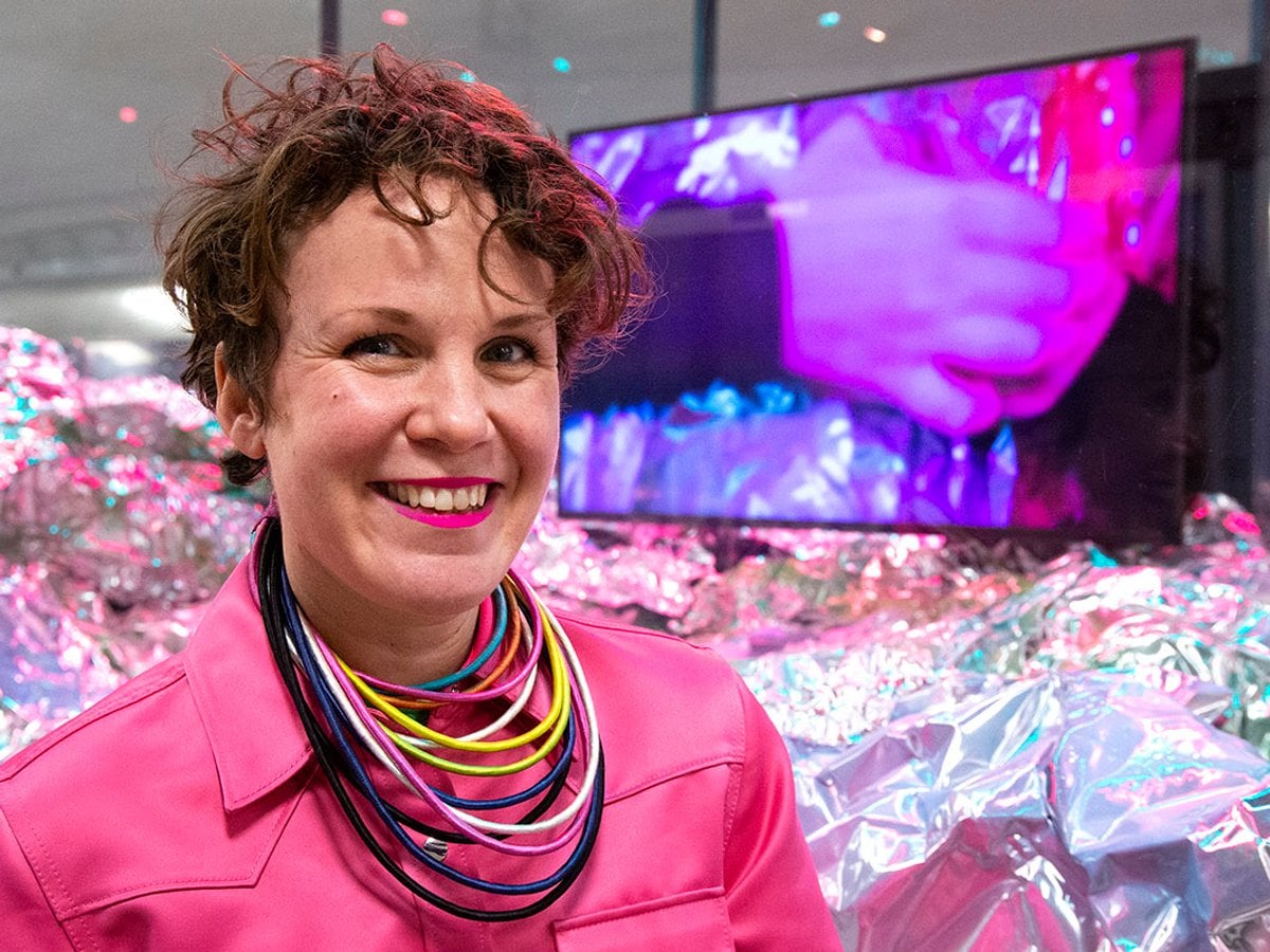 Alexandra ler mot kameran framför montern fylld med glittrande material på golvet.