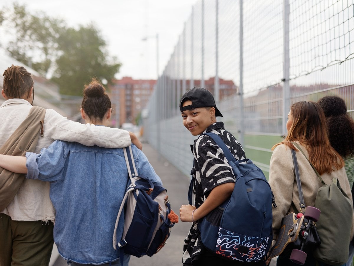 Fem ungdomar på stan går vid en fotbollsplan.

