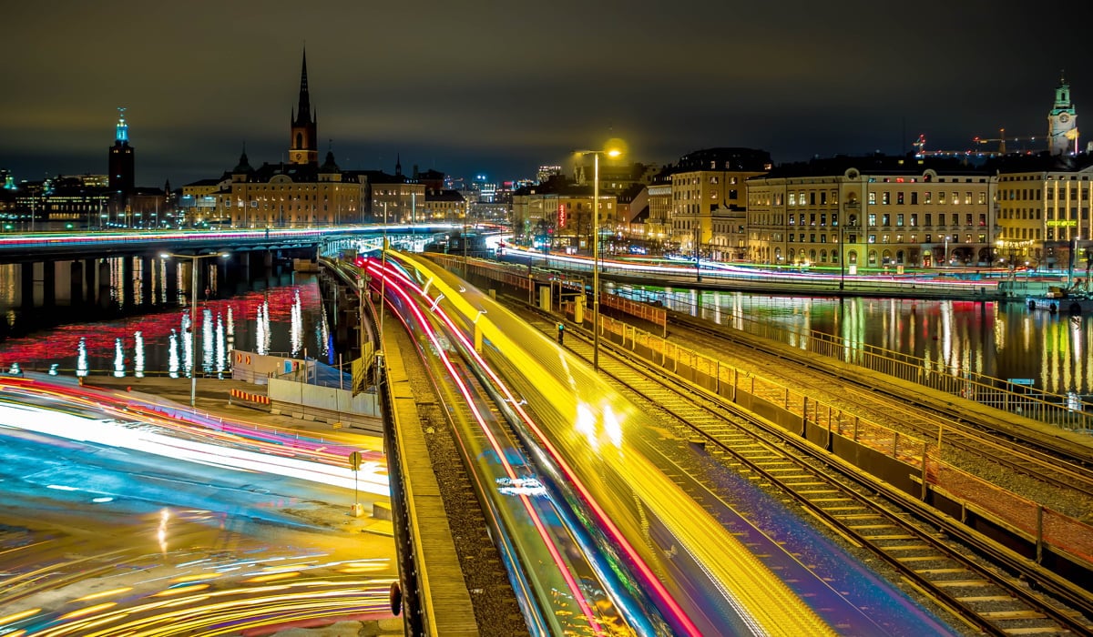 Nattbild över Strömbron tagen med lång slutartid. Bilar och tåg blir som ljusa streck i mörkret.