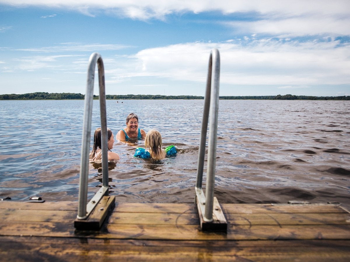 Bild tagen från bryggan på tre stycken som badar