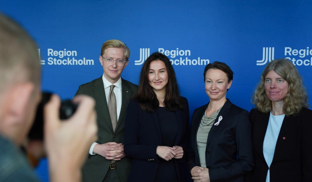 Foto på fyra politiker som står uppradade. I förgrunden syns en fotograf.